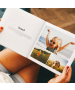 Photo Book With Text open on someone’s lap, showing a Travel chapter title on the left page and a collage of candid child photos on the right page – stylish layflat photo book with personalised text and images, lifestyle scene.