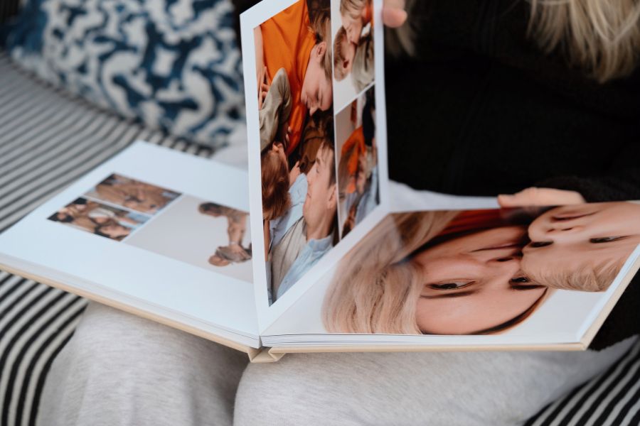 Person flipping through a premium layflat photo book with family photographs printed across seamless pages.